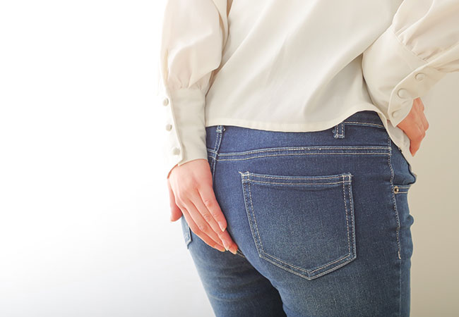 おしりを手でおさえる女性